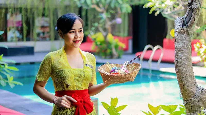 Staf hotel menawarkan keramahan Bali, salah satu 10 Kelebihan Sanur untuk Liburan Keluarga di Bali