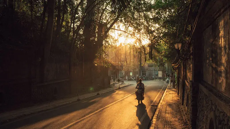 Pengendara motor di jalanan Ubud saat matahari terbenam.